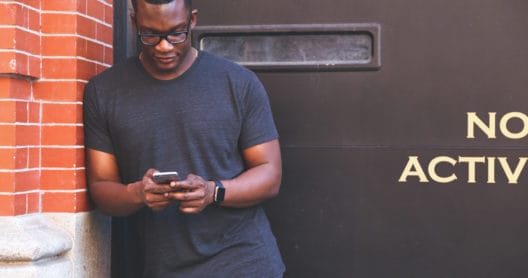 A person of color on phone outside a loading dock.