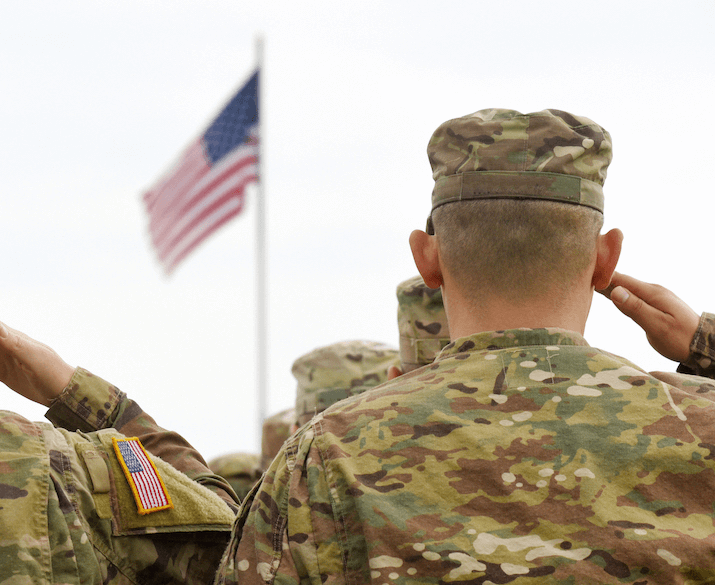 Military men in uniform saluting the American flag