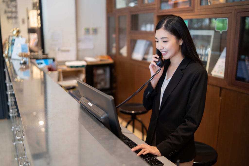 A hotel receptionist at the front desk on the phone.
