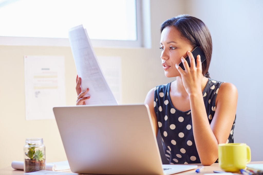 Women with laptop on the phone reviewing business reports.