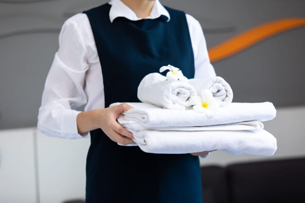 Hotel housekeeping staff holding freshly folded towels, showcasing the benefits of on-demand hiring solutions for efficient guest service.