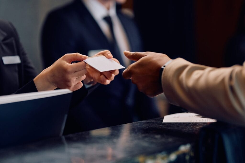 Hotel front desk staff handing a key card to a guest, illustrating seamless service and the impact of on-demand hiring solutions in the hospitality industry.